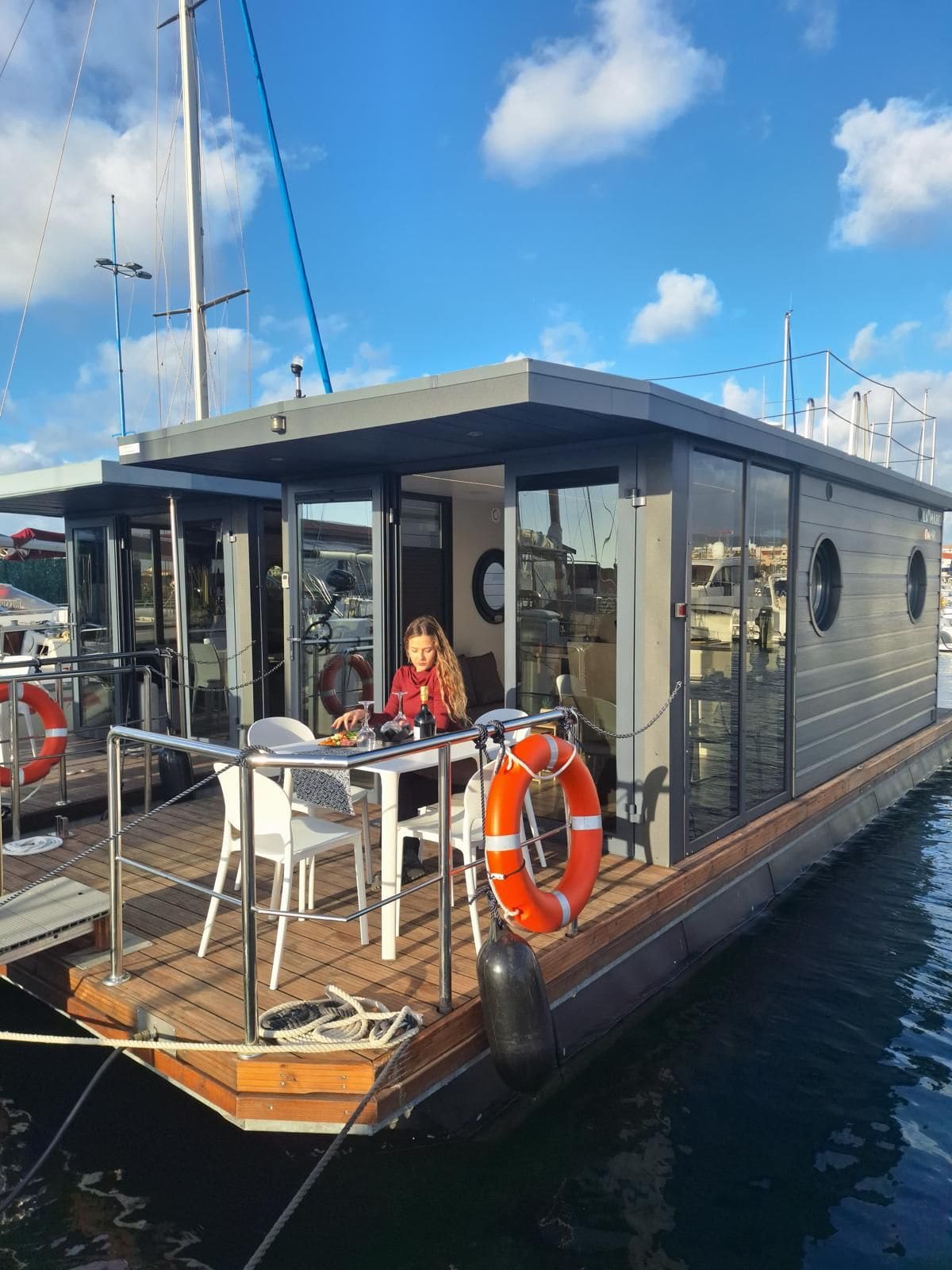 La houseboat sull'acqua, con un'ospite seduta in terrazza