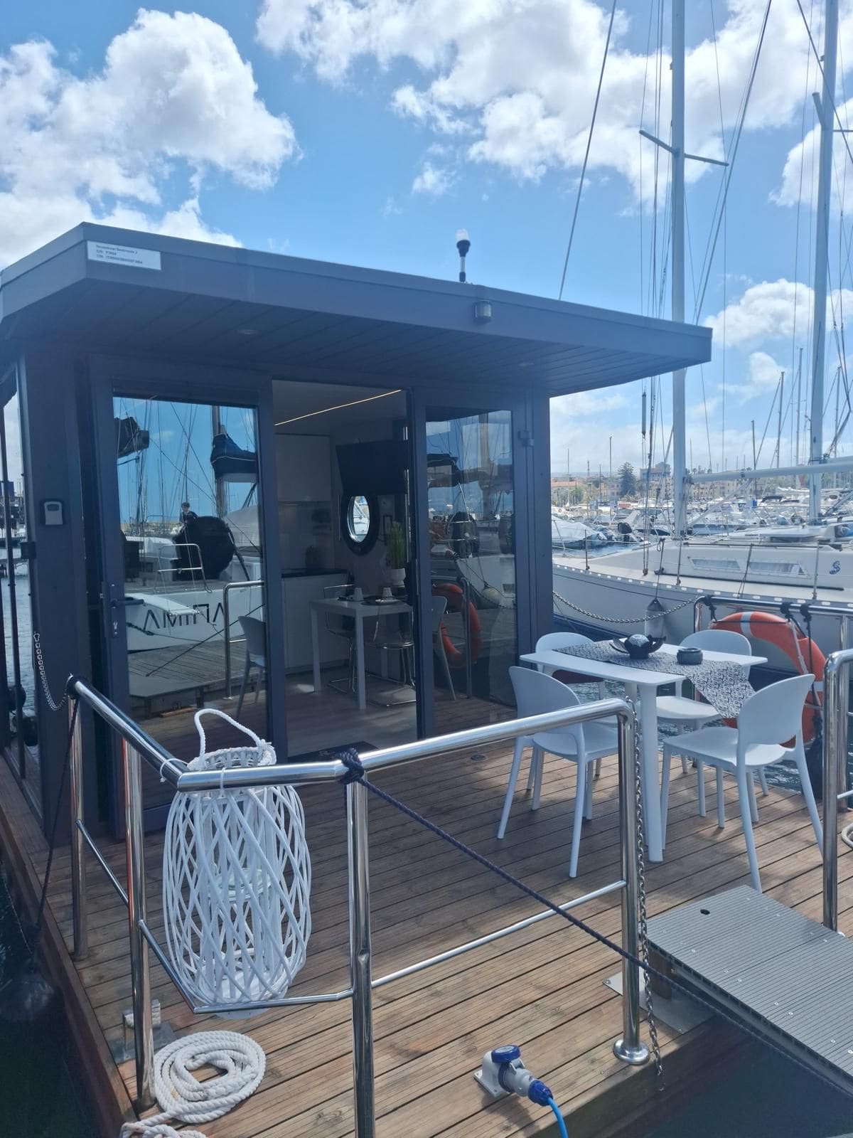La houseboat vista dal pontile: vetrate, terrazza in legno e tavolo all'aperto