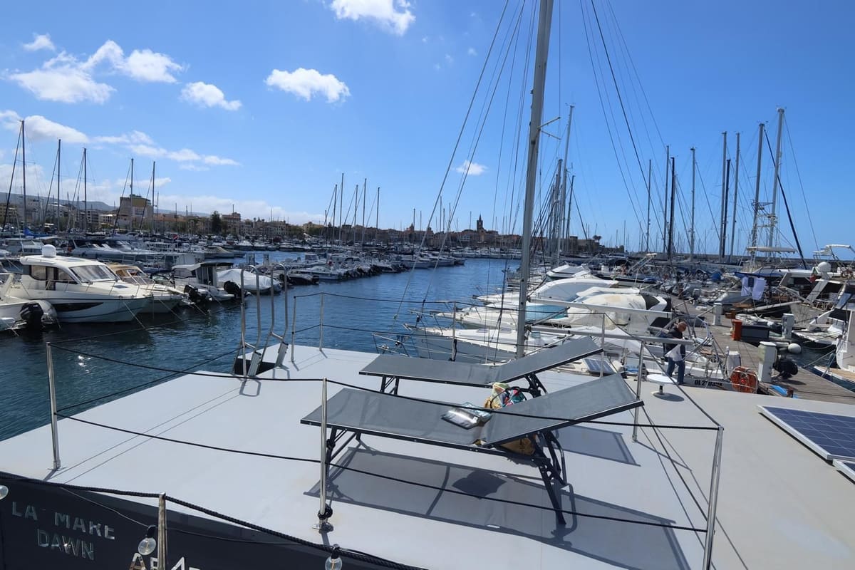Lettini sul solarium, con il porto e il centro storico di Alghero sullo sfondo
